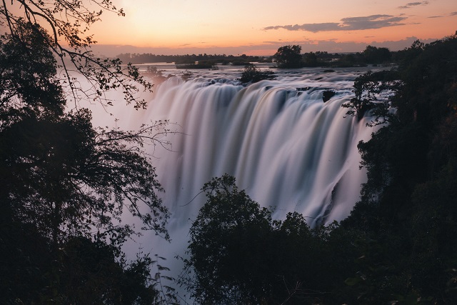 Water cascading over the Victoria Falls as the sun sets - Image Credit: BBC. Photographer: Jacob Robinson